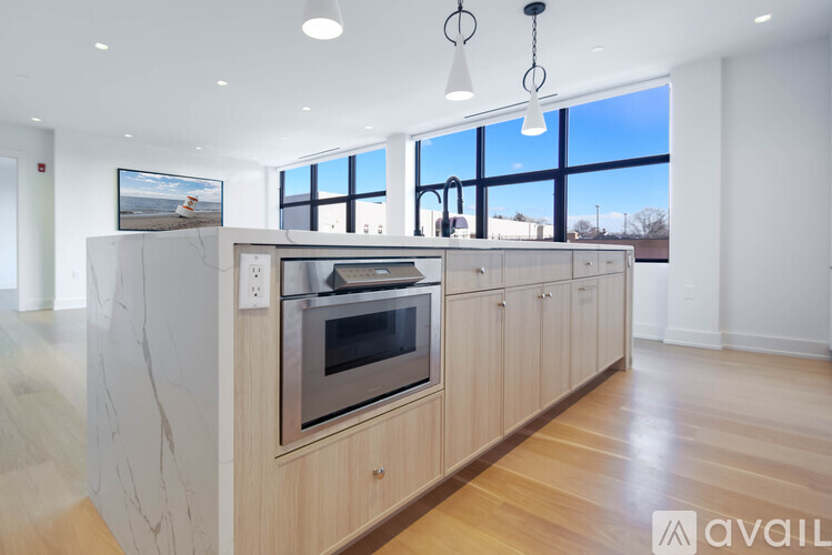 A modern kitchen with wooden cabinets and a large window.