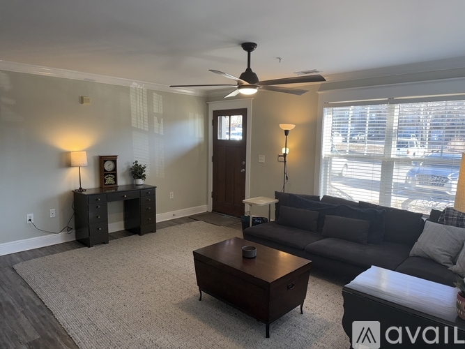 A living room with a couch, coffee table, and a fan.