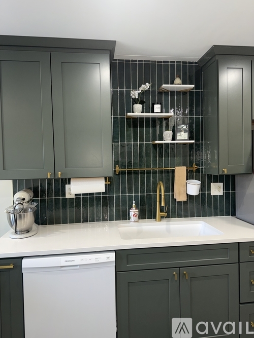 A kitchen with dark green cabinets and a white dishwasher.