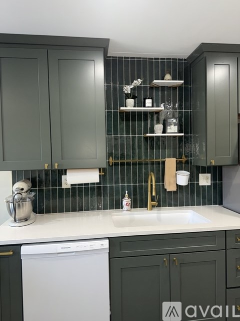 A kitchen with dark green cabinets and a white dishwasher.