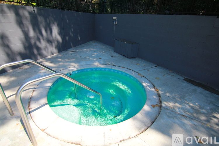 A hot tub with a metal frame is surrounded by a concrete floor.