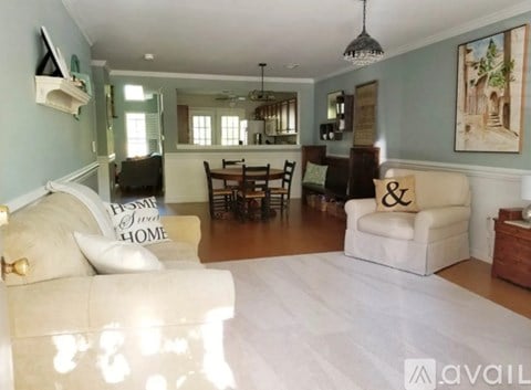A living room with a white couch and a white pillow that says "Home Sweet Home".
