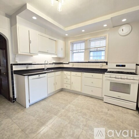 A kitchen with white cabinets and black countertops.