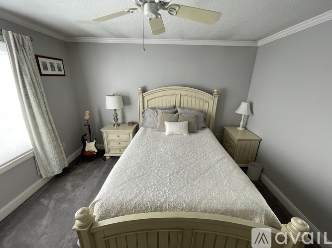 A bedroom with a bed, two lamps, and a guitar.