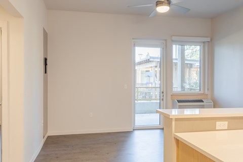 A room with a ceiling fan and a window with a view of a building outside.