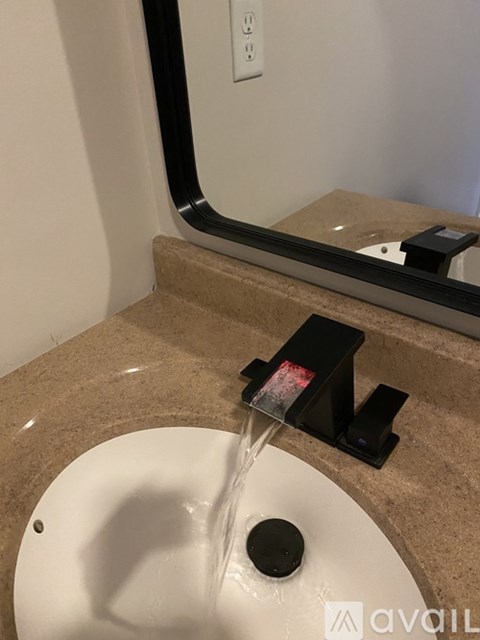 A white sink with a black faucet is turned on.