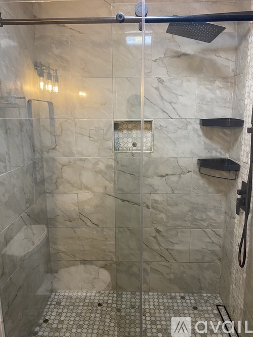 A shower with a glass door and a tiled floor.