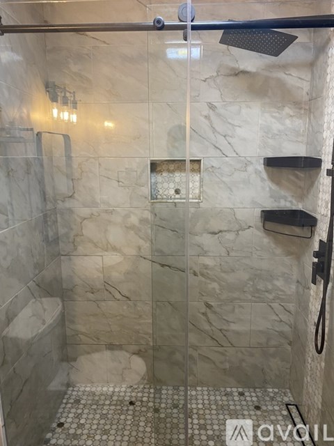 A shower with a glass door and a tiled floor.