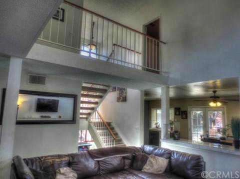 A living room with a brown leather couch and a staircase in the background.