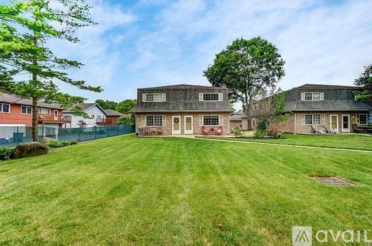 A large grassy yard with a house and a tree in the background.