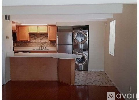 A kitchen with wooden cabinets and a stainless steel dishwasher.