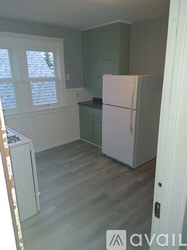 A kitchen with a white fridge and wooden floors.