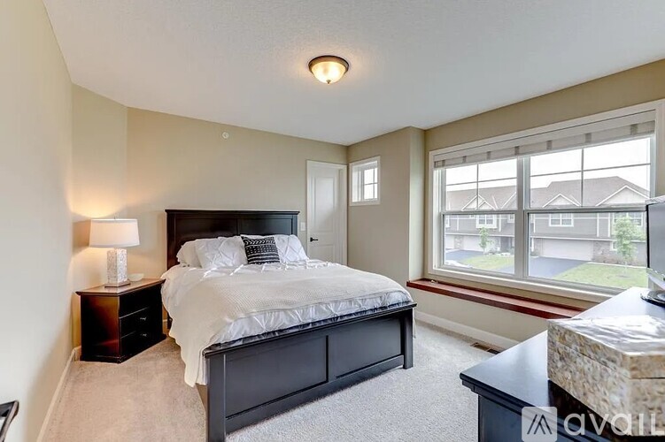 A bedroom with a large bed and a window overlooking a residential area.