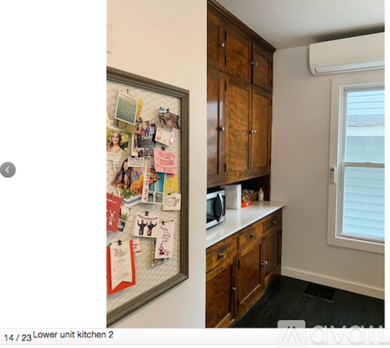 A kitchen with a refrigerator covered in magnets and a microwave on the counter.