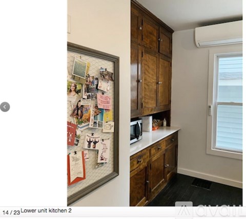 A kitchen with a refrigerator covered in magnets and a microwave on the counter.