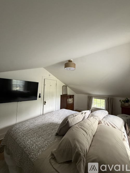 A bedroom with a bed, a television, and a window.