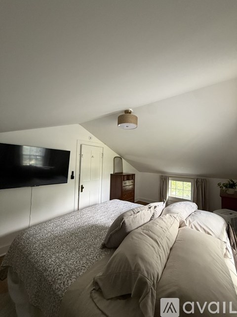 A bedroom with a bed, a television, and a window.
