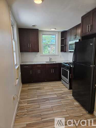 A kitchen with a black fridge and wooden flooring.