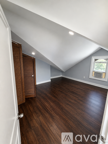A room with wooden floors and a window with blinds.