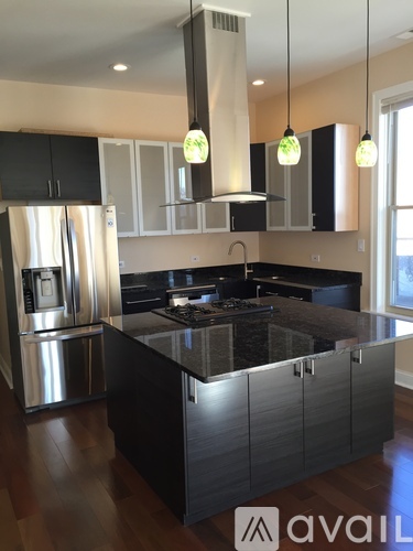 A modern kitchen with a black countertop and stainless steel appliances.