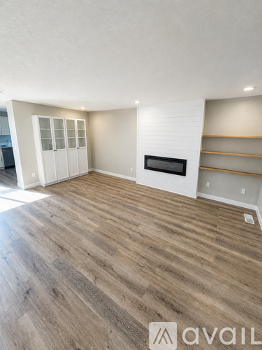 A spacious room with wooden flooring and a fireplace.
