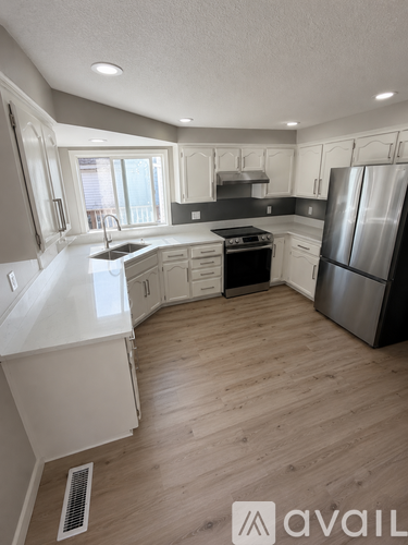 A modern kitchen with wooden floors and stainless steel appliances.