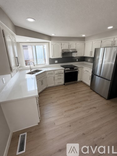 A modern kitchen with wooden floors and stainless steel appliances.