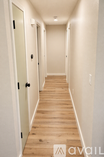 A long hallway with white walls and wood flooring.