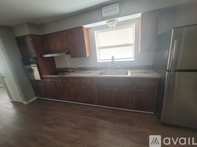 A kitchen with brown cabinets and a stainless steel refrigerator.
