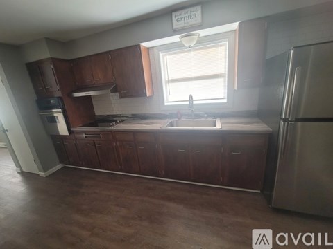 A kitchen with brown cabinets and a stainless steel refrigerator.