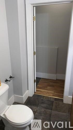 A white toilet in a small bathroom with a door open to a hallway.