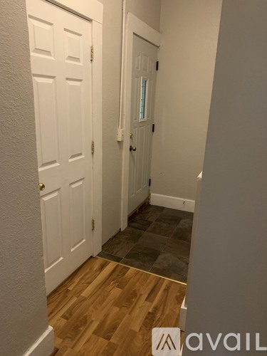 A hallway with a white door and a wooden floor.