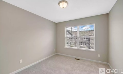 A room with a window and a carpeted floor.