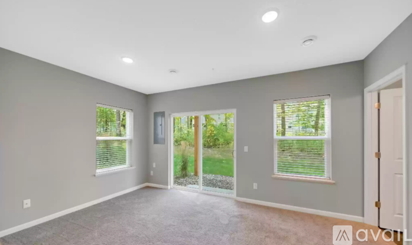 A spacious room with a carpeted floor and a sliding glass door leading to a garden.