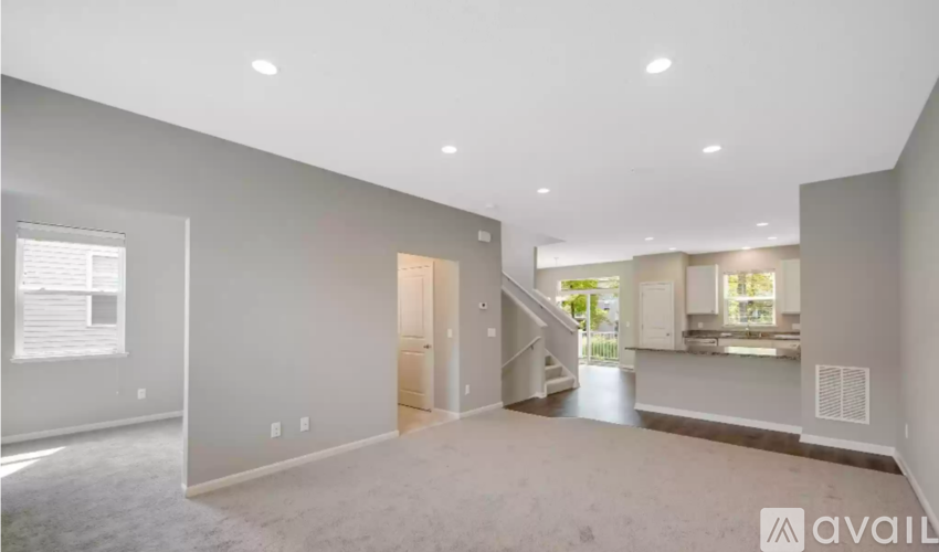 A spacious living room with a staircase leading to another room.