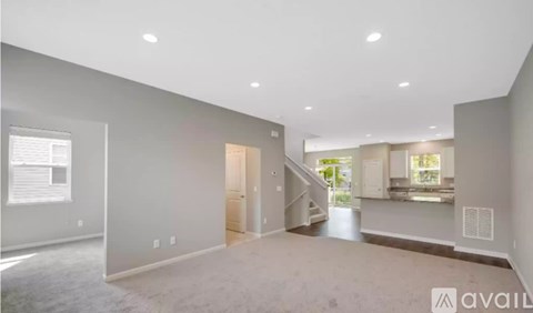 A spacious living room with a staircase leading to another room.