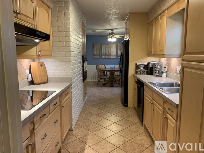 A kitchen with wooden cabinets and a black refrigerator.