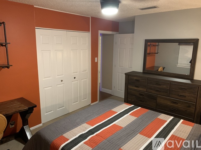 A bedroom with orange walls and a bed with a striped comforter.