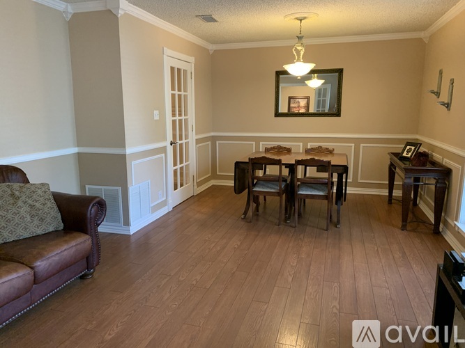 A living room with a brown leather couch and a wooden table.