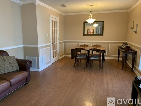 A living room with a brown leather couch and a wooden table.