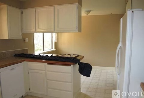 A kitchen with white cabinets and a white refrigerator.