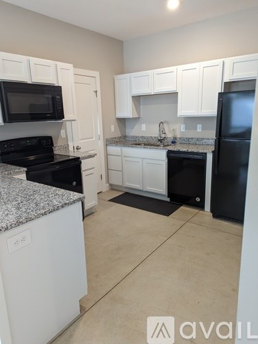 A kitchen with white cabinets and black appliances.