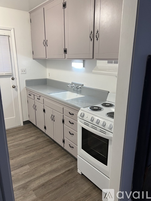 A kitchen with white cabinets and a white stove.