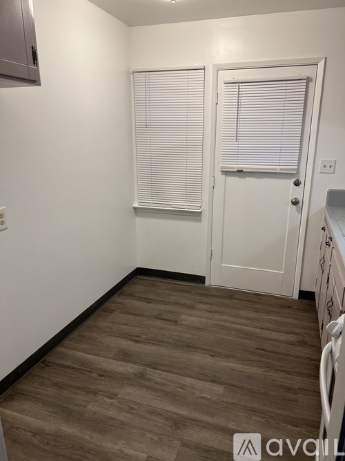 A room with a white door and a wooden floor.