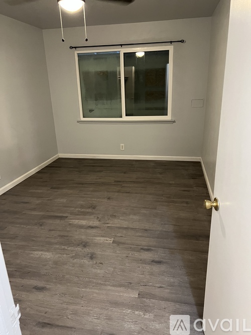 A room with a window and wooden flooring.