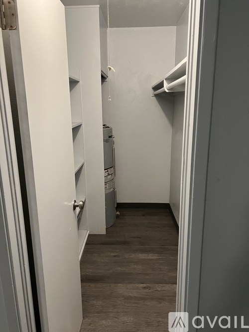 A narrow hallway with a door on the left and a shelf on the right.