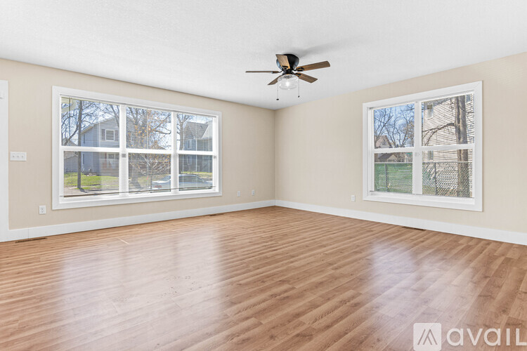 A spacious room with a ceiling fan and two windows.