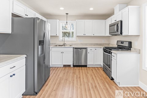 A kitchen with white cabinets and a wooden floor.