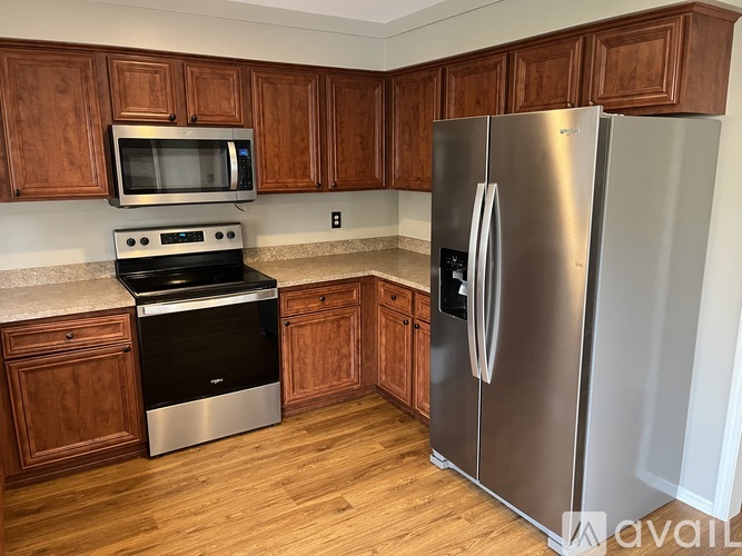 A kitchen with wooden cabinets and a stainless steel refrigerator.