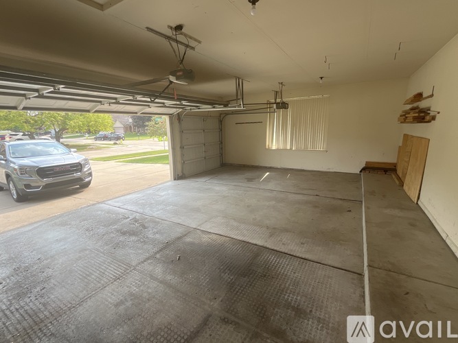 A spacious garage with a car parked on the left side and a wooden board on the right side.